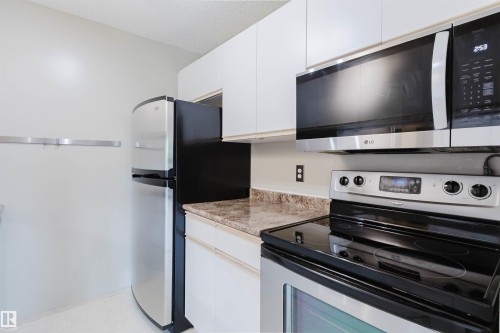 Stainless steel appliances, white cabinetry, integrated microwave, and a black cooktop - #316 17109 67 Av Nw, Edmonton, AB 