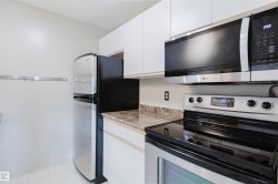 Stainless steel appliances, white cabinetry, integrated microwave, and a black cooktop - 
