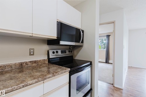 White cabinetry with brushed nickel hardware, laminate countertops, and stainless steel appliances - #316 17109 67 Av Nw, Edmonton, AB 