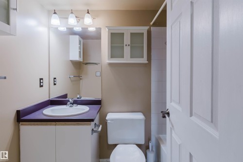 Bathroom with a single vanity, undermount sink, wall-mounted mirror, and white panel door - #316 17109 67 Av Nw, Edmonton, AB 