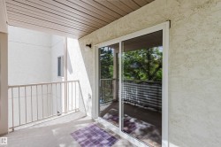 Balcony with a textured stucco exterior, white metal railing, and a sliding glass door - 