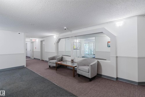 Hallway featuring a wall-mounted mirror, multiple wall sconces, and overhead lighting - #316 17109 67 Av Nw, Edmonton, AB 