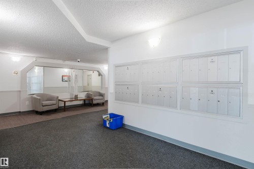 Lobby area featuring wall-mounted mailboxes, sconce lighting, and carpet flooring - #316 17109 67 Av Nw, Edmonton, AB 