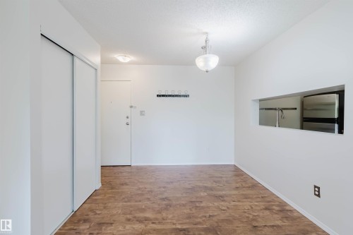 Hardwood-finish flooring, built-in coat rack, translucent glass chandelier, pass-through window, and sliding wardrobe doors - #316 17109 67 Av Nw, Edmonton, AB 