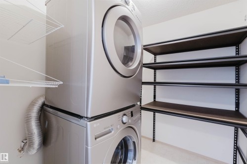 Stacked laundry appliances with metal shelves, and wire rack storage - #316 17109 67 Av Nw, Edmonton, AB 