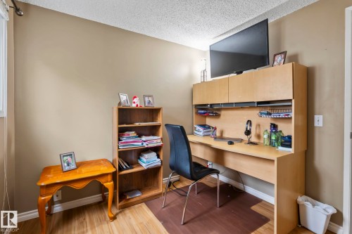 Wood-finish flooring, neutral wall paint, and a built-in light wood-finish desk with upper cabinetry - 716 Clareview Rd Nw, Edmonton, AB 