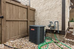 Brown wood fence with black latch, textured stucco exterior, river rock ground covering, and a gray utility meter - 