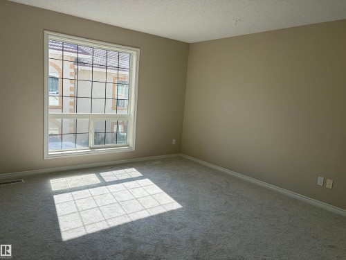 Neutral-toned walls complement plush carpet flooring - #100 13825 155 Av Nw, Edmonton, AB 