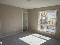 Neutral tone wall paint, light gray carpeting, white trim, and a window with grid inserts - 
