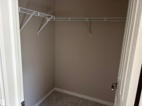 Built-in wire shelving, neutral wall paint, and gray carpeted flooring - #100 13825 155 Av Nw, Edmonton, AB 