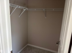 Built-in wire shelving, neutral wall paint, and gray carpeted flooring - 