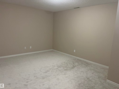 Neutral wall paint, textured ceiling, and light-colored carpeting - #100 13825 155 Av Nw, Edmonton, AB 