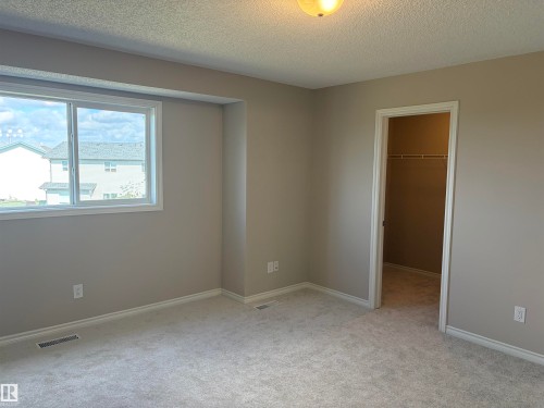 Wall-to-wall carpeting, neutral wall finishes, and a single window with white trim - #100 13825 155 Av Nw, Edmonton, AB 