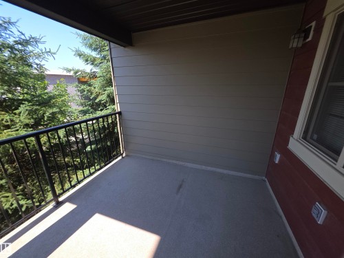 Outdoor balcony with a black metal railing and concrete flooring - #206 12045 22 Av Sw, Edmonton, AB 
