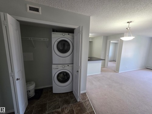 Integrated laundry closet with stacked appliances - #206 12045 22 Av Sw, Edmonton, AB 