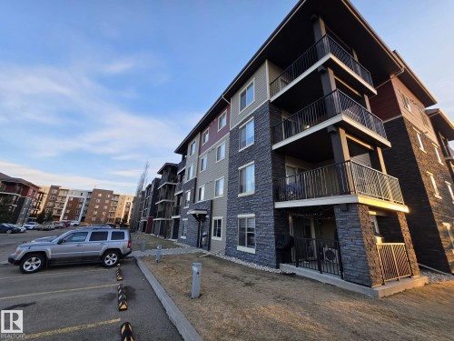 Multi-story building with stacked balconies, dark stone veneer siding, and contrasting light siding - #206 12045 22 Av Sw, Edmonton, AB 