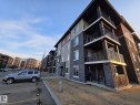 Multi-story building with stacked balconies, dark stone veneer siding, and contrasting light siding - #206 12045 22 Av Sw, Edmonton, AB 