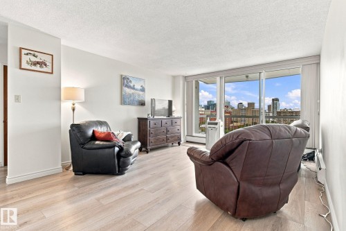 Light wood-finish flooring, white walls, large windows, and a cityscape backdrop - #1507 9835 113 St Nw, Edmonton, AB 
