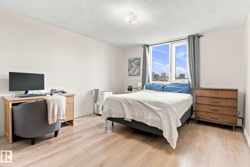 Light wood-finish flooring, white walls, and a large window with city scenery - #1507 9835 113 St Nw, Edmonton, AB 