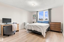 Light wood-finish flooring, white walls, and a large window with city scenery - 