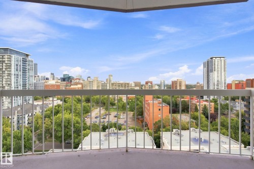 Balcony with painted concrete flooring and white metal railings overlooking a city skyline, urban trees, and buildings - #1507 9835 113 St Nw, Edmonton, AB 