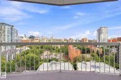 Balcony with painted concrete flooring and white metal railings overlooking a city skyline, urban trees, and buildings - 
