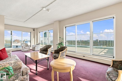 Expansive room with multiple sliding glass doors opening to an outdoor terrace, featuring a textured ceiling and recessed lighting - #1507 9835 113 St Nw, Edmonton, AB 