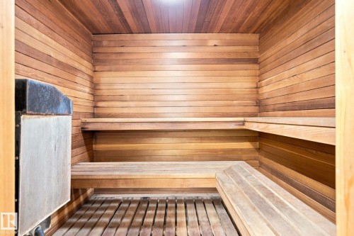Wood-paneled sauna with built-in tiered benches, slatted wood flooring, and a wall-mounted heater - #1507 9835 113 St Nw, Edmonton, AB 