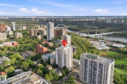 High-rise building situated within an urban landscape, featuring river access and surrounding green spaces - 
