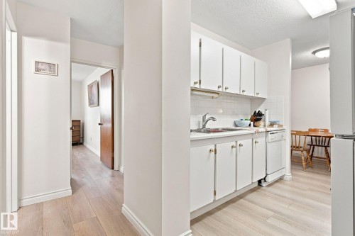 Kitchen with white cabinetry, white tile backsplash, and wood-finish flooring - #1507 9835 113 St Nw, Edmonton, AB 