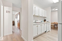 Kitchen with white cabinetry, white tile backsplash, and wood-finish flooring - 