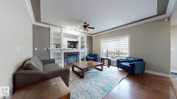 Hardwood flooring, tray ceiling, built-in shelving, stone-finish fireplace, and window with blinds - 