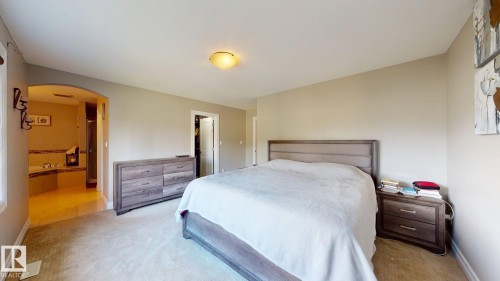 Neutral wall color, carpeted flooring, arched doorway, recessed lighting, and a built-in tub with tiled surround - 1232 Cunningham Drive Sw, Edmonton, AB 