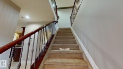Carpeted staircase with wrought iron balusters and dark wood handrails - 