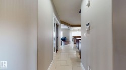 Tile flooring extending through a hallway with light-colored walls and a door featuring glass panels - 