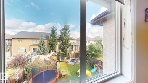 Expansive fenced backyard featuring mature evergreen trees and a manicured lawn - 1232 Cunningham Drive Sw, Edmonton, AB 
