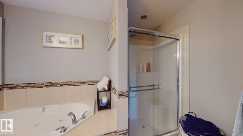 Built-in corner soaking tub with deck-mounted faucet, complemented by a walk-in shower with a glass enclosure and recessed lighting - 1232 Cunningham Drive Sw, Edmonton, AB 