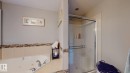 Built-in corner soaking tub with deck-mounted faucet, complemented by a walk-in shower with a glass enclosure and recessed lighting - 1232 Cunningham Drive Sw, Edmonton, AB 