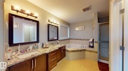 Dual vanity with undermount sinks and extensive countertop space, an oversized soaking tub, tile flooring, and a glass-enclosed shower - 