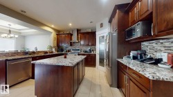 Kitchen featuring wood-finish cabinetry, stainless steel appliances, granite countertops, and a tile backsplash - 