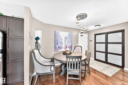 Wood-finish flooring with a modern pendant light fixture - #418 279 Suder Greens Dr Nw, Edmonton, AB 
