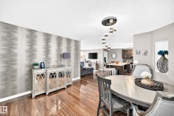 Wood-finish flooring, accent wall with textured wallpaper, recessed wall niche, and an open-concept living area - 