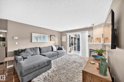 Living area featuring a fireplace with a stone surround, a white mantel, and wood-finish flooring - 