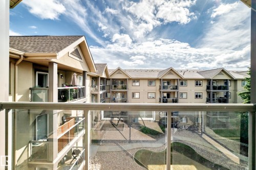 Private balcony with glass railings overlooking a multi-story building and courtyard - #418 279 Suder Greens Dr Nw, Edmonton, AB 