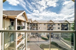 Private balcony with glass railings overlooking a multi-story building and courtyard - 