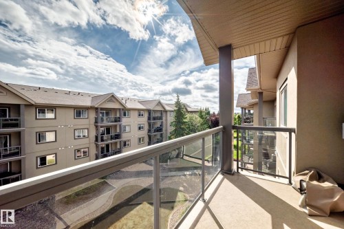 Private balcony featuring a glass panel railing, concrete flooring, and an overhead soffit - #418 279 Suder Greens Dr Nw, Edmonton, AB 