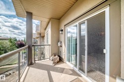 Private balcony featuring a glass railing, sliding glass door, and exterior wall sconce - 