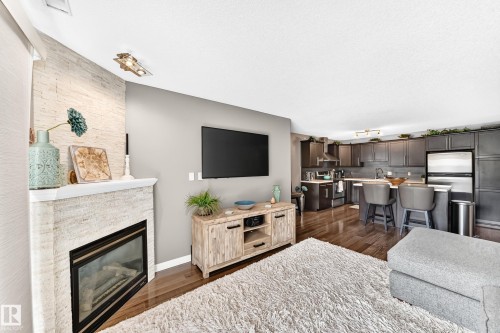 Corner fireplace with a white mantel and textured surround - #418 279 Suder Greens Dr Nw, Edmonton, AB 