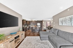 Open-concept design featuring wood-finish flooring, recessed lighting, and a modern kitchen with dark cabinetry and stainless steel appliances - 