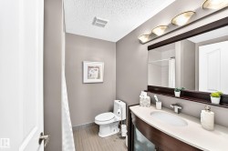 Curved dark wood vanity with a light-toned countertop, oval undermount sink, and polished chrome faucet - 